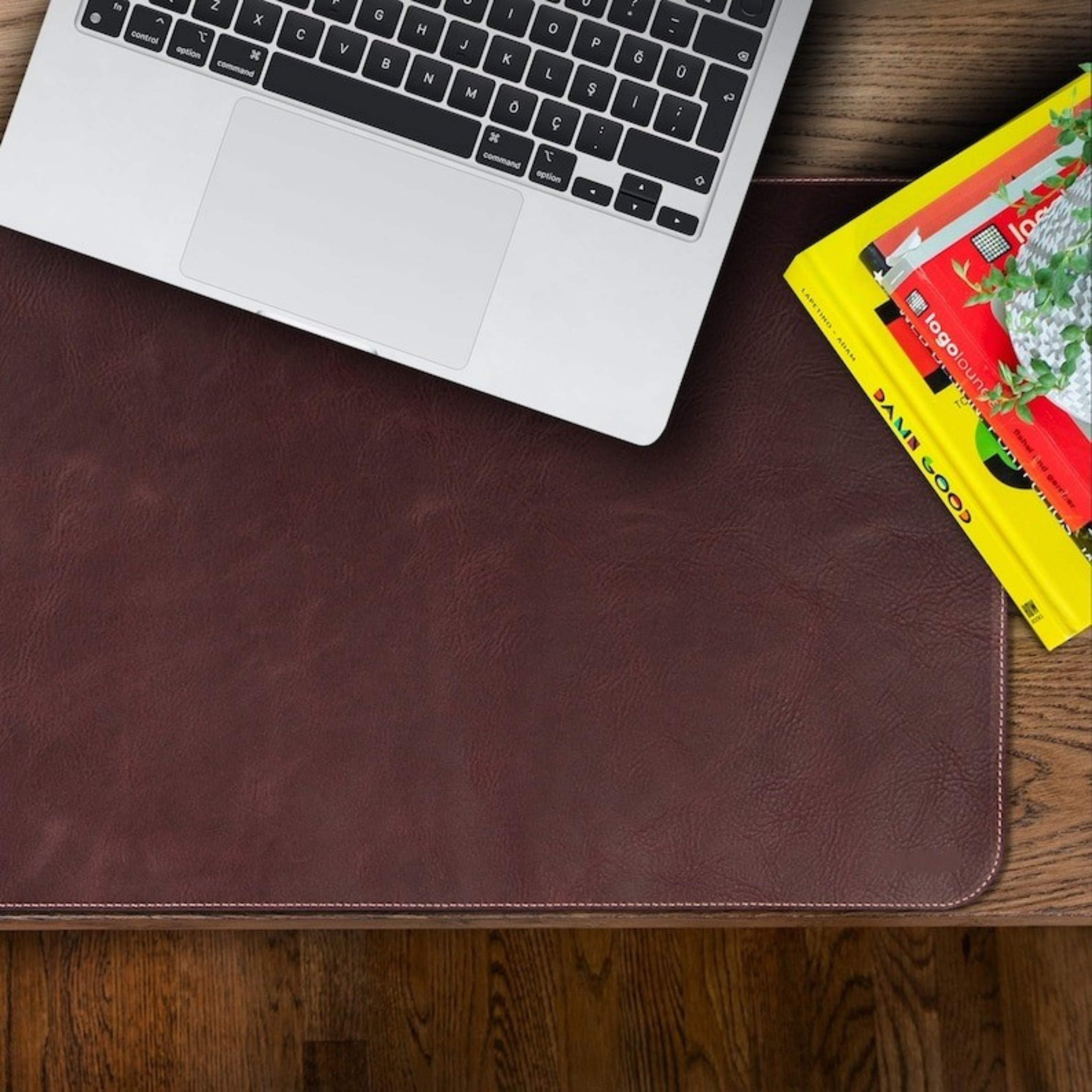 Laptop on a brown leather desk pad with books underneath